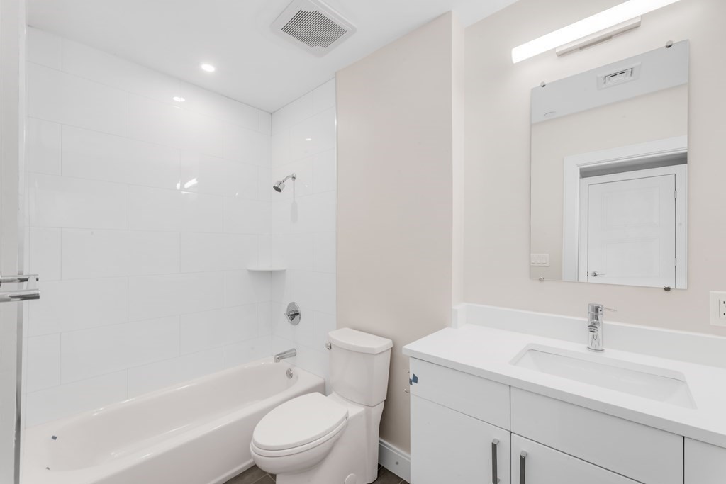 425 Lagrange Street, Unit 109 Boston, MA 02132 - Photo 34 of 42 a bathroom with a sink toilet vanity granite tub and shower