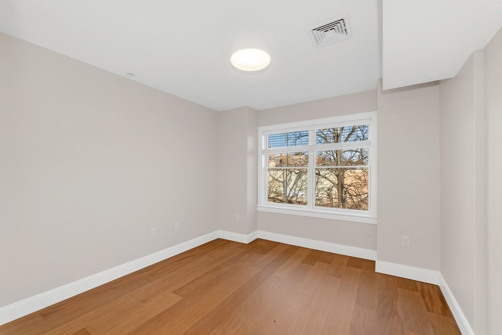 425 Lagrange Street, Unit 109 Boston, MA 02132 - Photo 35 of 42 an empty room with wooden floor and windows