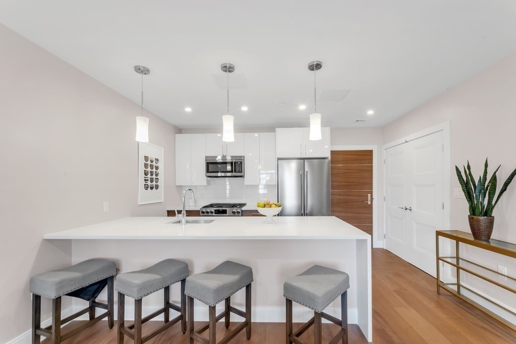 425 Lagrange Street, Unit 109 Boston, MA 02132 - Photo 4 of 42 a kitchen with kitchen island granite countertop a sink and chairs