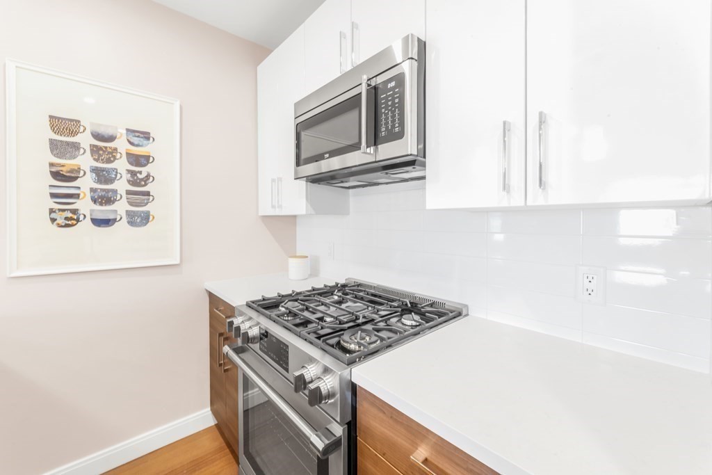 425 Lagrange Street, Unit 109 Boston, MA 02132 - Photo 8 of 42 a kitchen with stainless steel appliances granite countertop a stove and a microwave