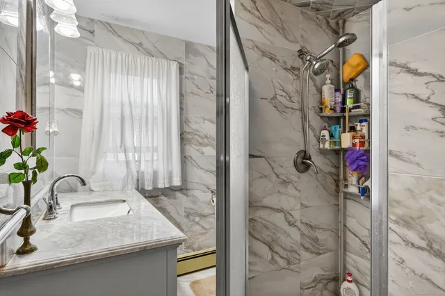a bathroom with a granite countertop sink a mirror and shower