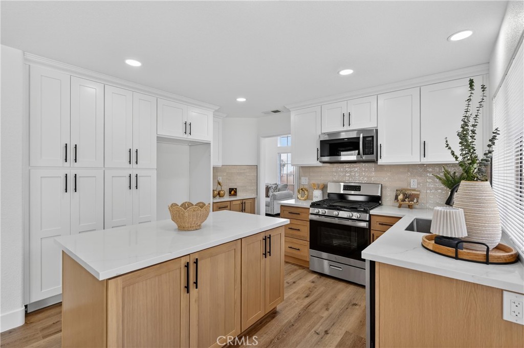 21484 Dickinson Road Moreno Valley, CA 92557 - Photo 15 of 48 a kitchen with a sink a stove a refrigerator and white cabinets