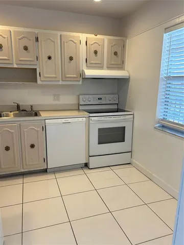 a kitchen with white cabinets appliances and a sink