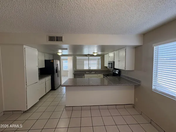 a large white kitchen with a fireplace and a large window