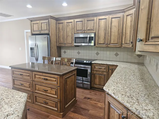 a kitchen with stainless steel appliances granite countertop a stove a sink and a microwave