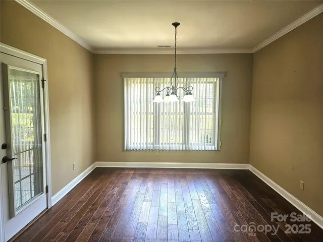 a view of an empty room with wooden floor fridge and a window