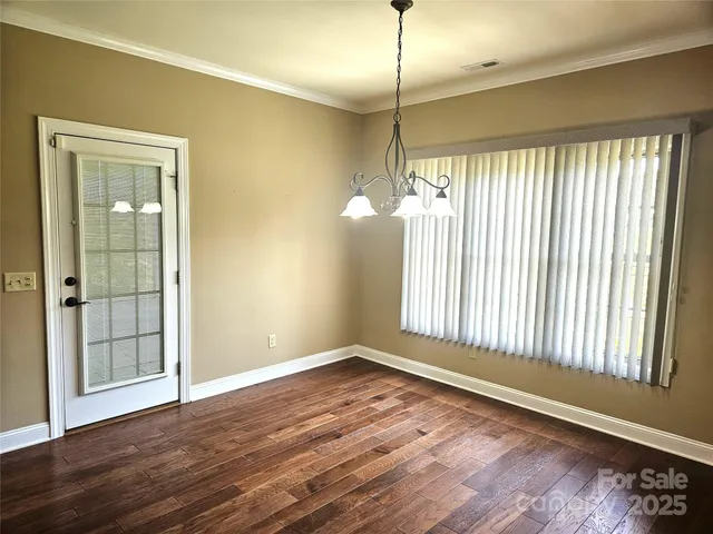 an empty room with wooden floor outdoor view and windows