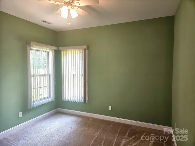 an empty room with windows and chandelier fan