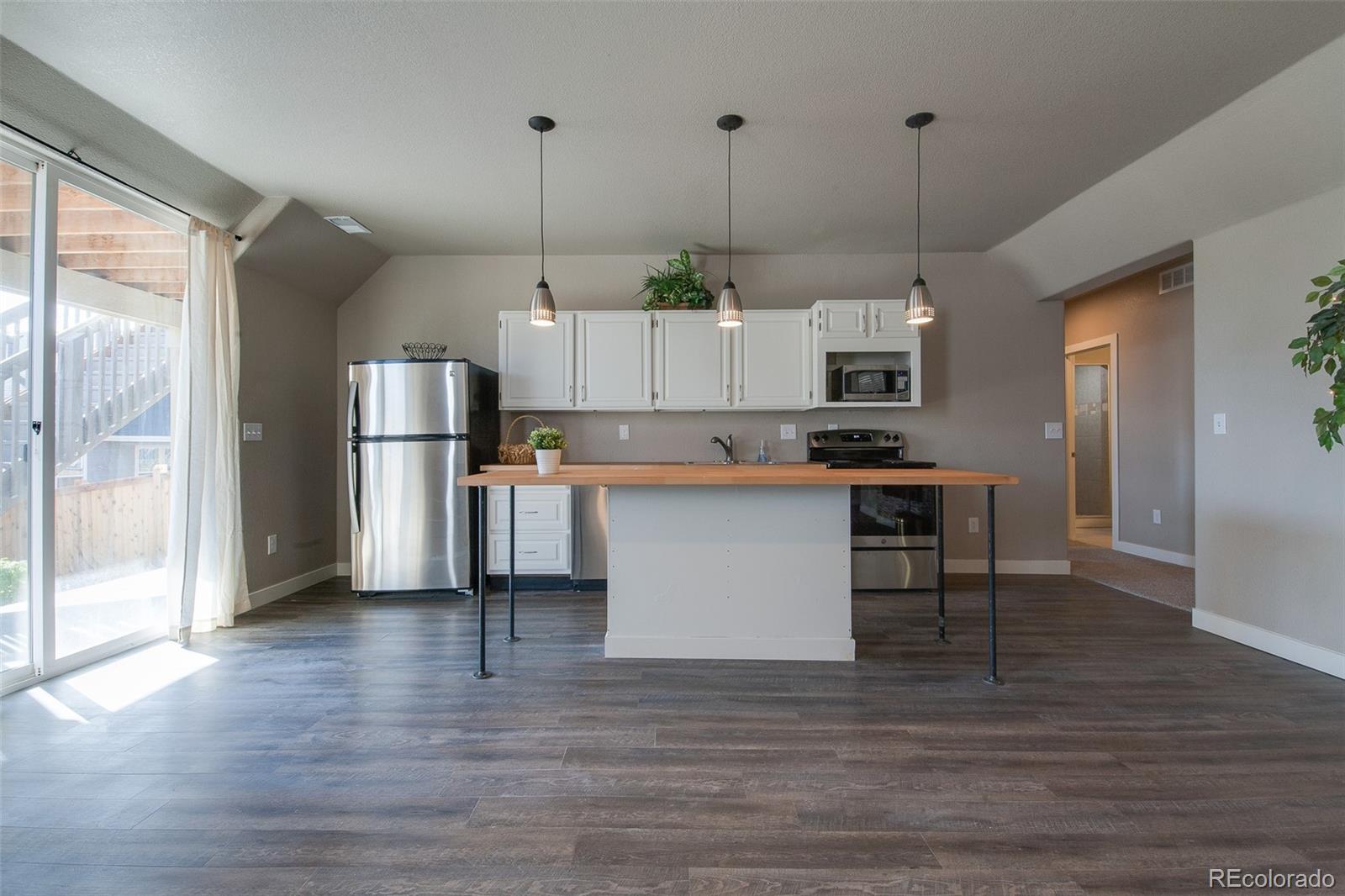 Undisclosed Address Castle Rock, CO 80104 - Photo 4 of 19 a kitchen view with stainless steel appliances kitchen island granite countertop a refrigerator a stove and white cabinets with wooden floor