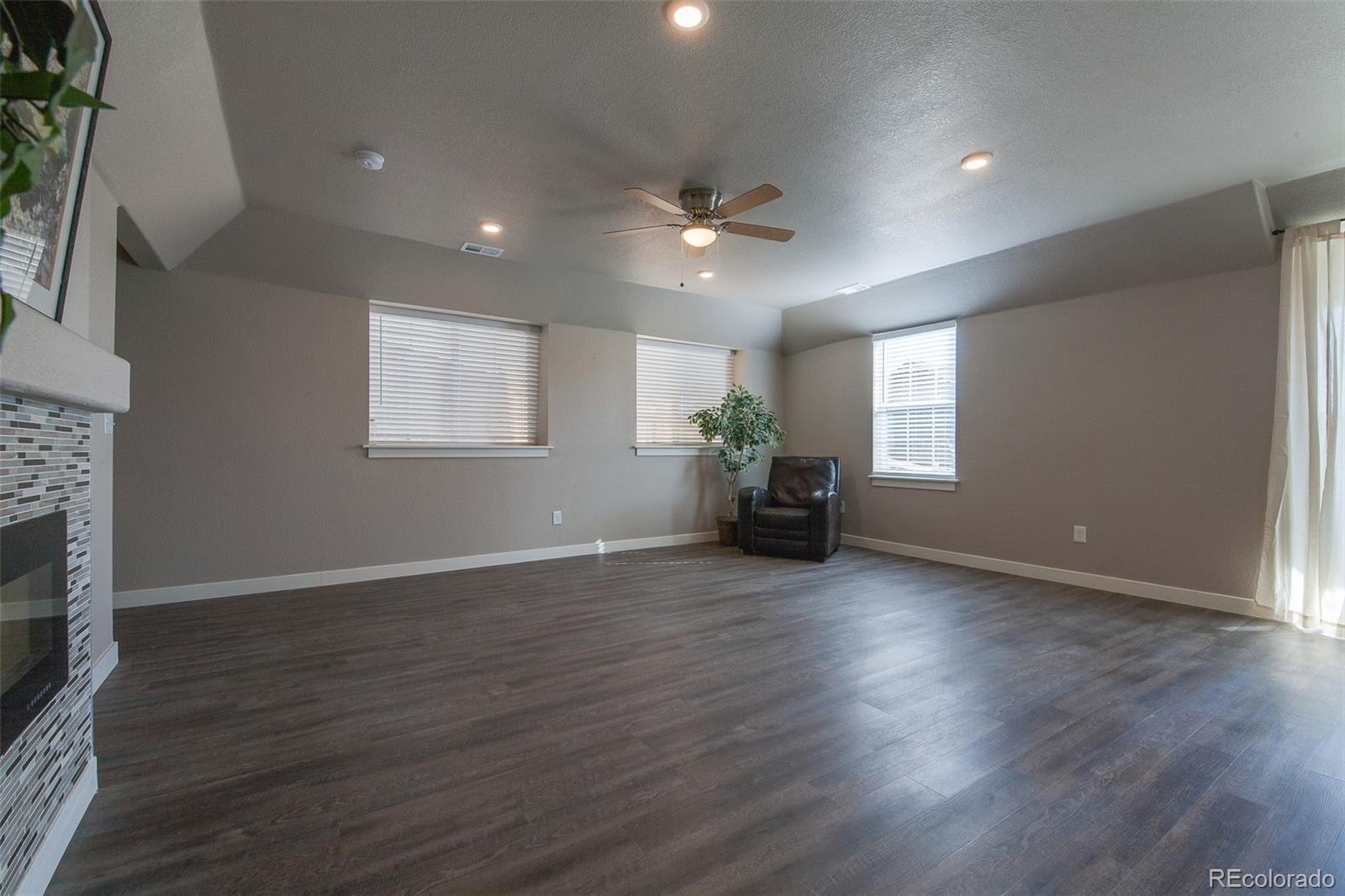 Undisclosed Address Castle Rock, CO 80104 - Photo 5 of 19 an empty room with wooden floor fireplace and windows