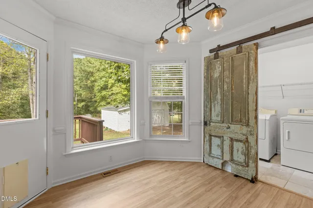 a view of an empty room with a window and wooden floor