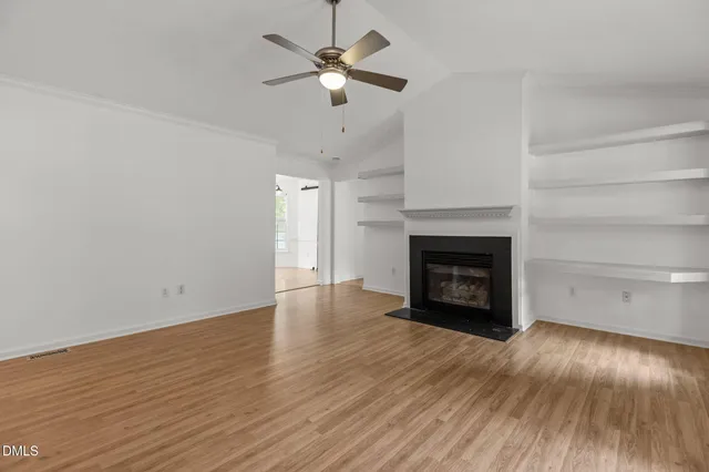 a view of an empty room with wooden floor fireplace and a window