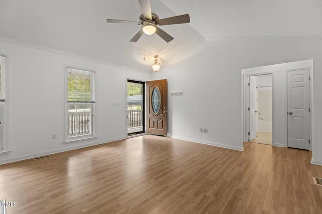a view of an empty room with wooden floor and a window