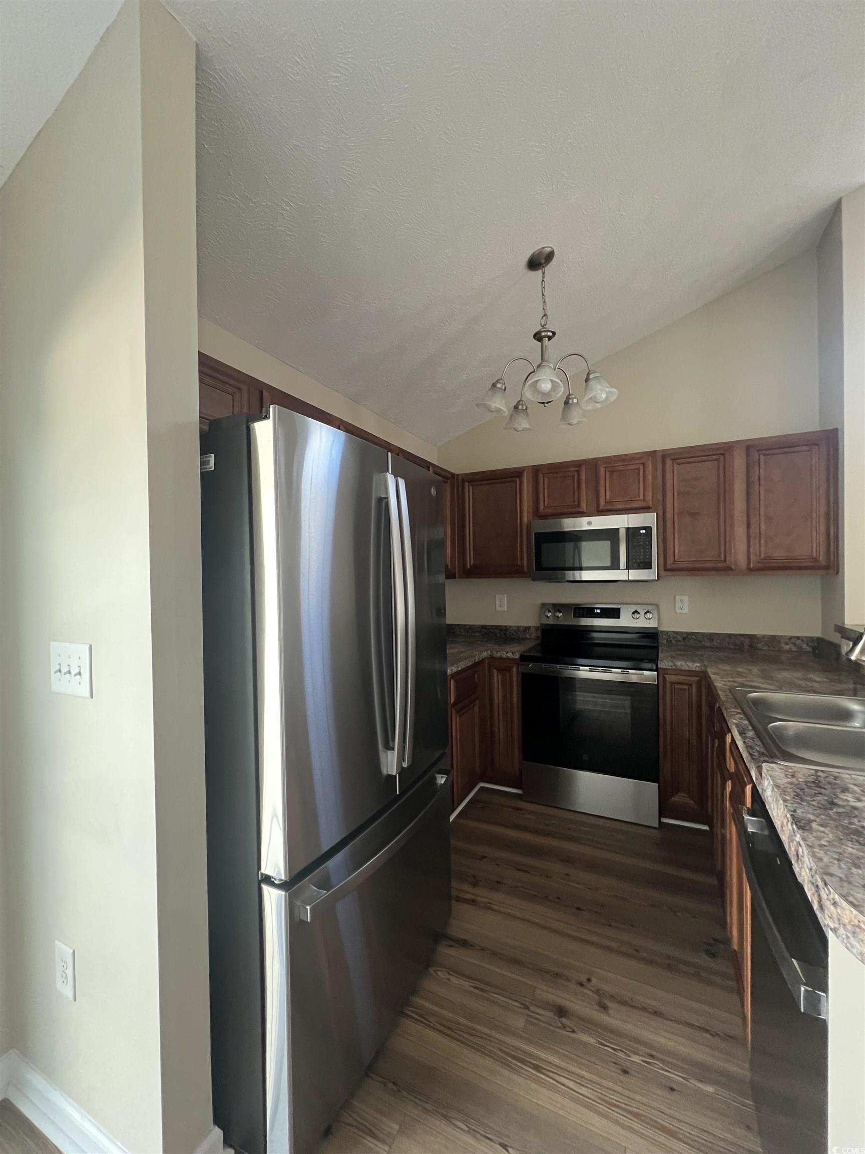 225 Upper Saddle Circle Conway, SC 29526 - Photo 8 of 24 Kitchen featuring stainless steel appliances, vaulted ceiling, dark countertops, decorative light fixtures, and dark wood-type flooring