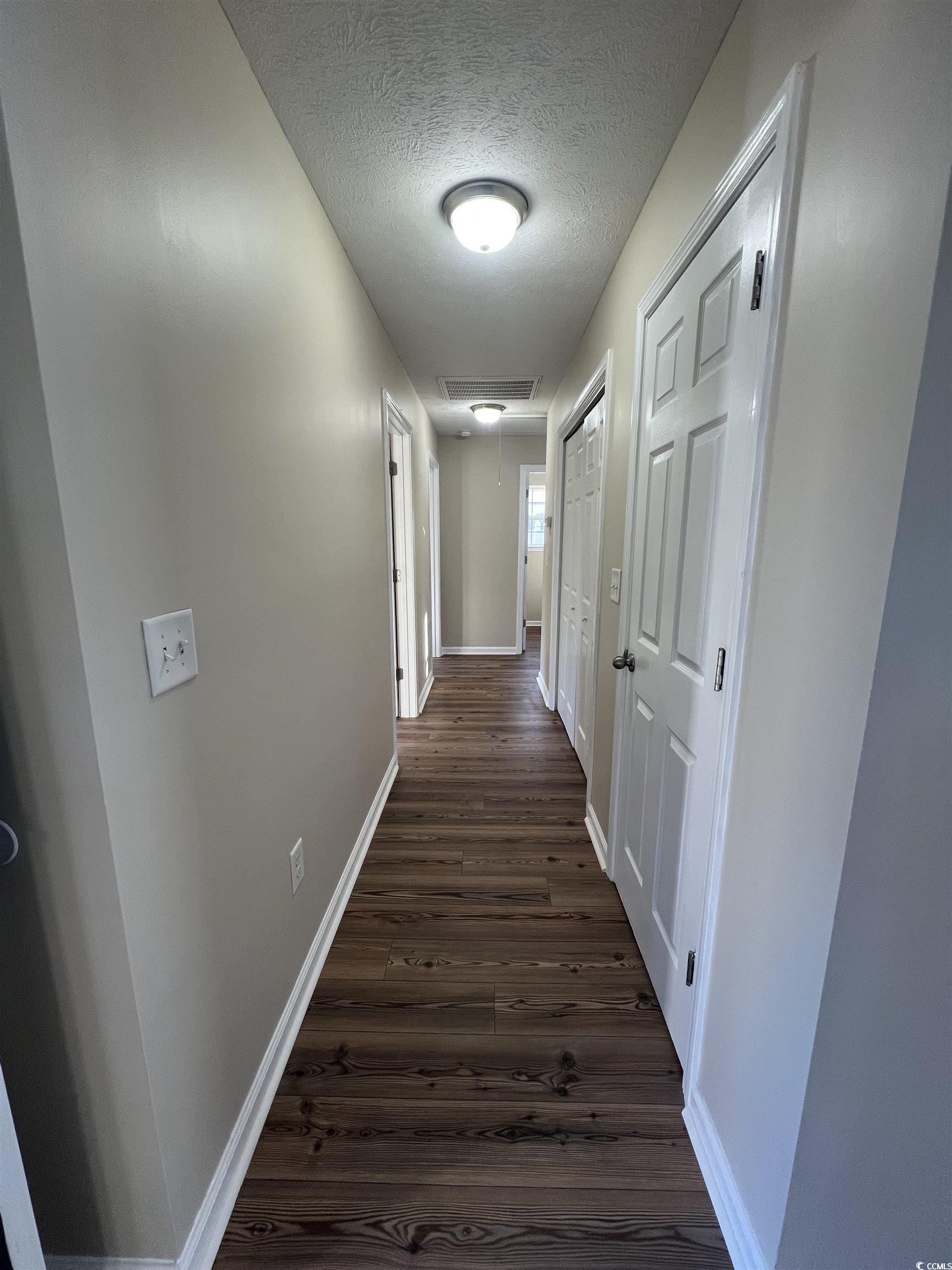 225 Upper Saddle Circle Conway, SC 29526 - Photo 10 of 24 Hall with attic access, dark wood-style floors, and a textured ceiling
