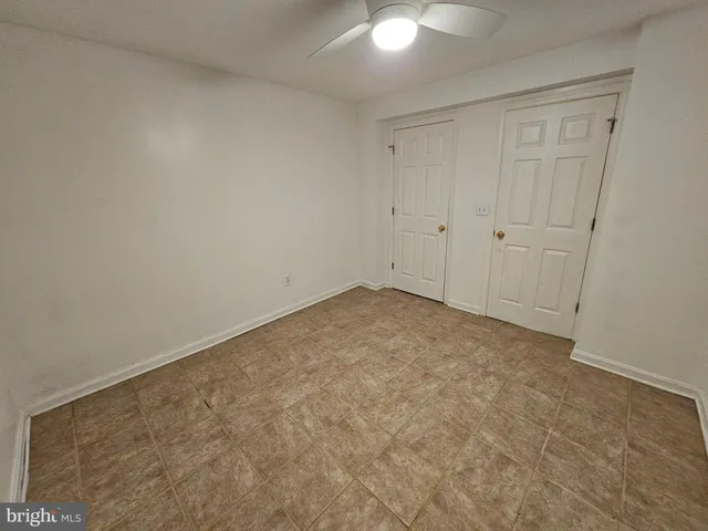 an empty room with a fan & a window