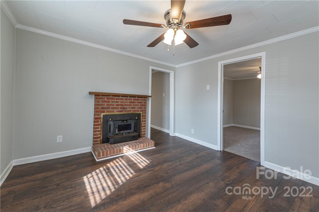 872 State Rd S-29-376 Lancaster, SC 29720 - Photo 13 of 15 an empty room with wooden floor a ceiling fan a fireplace and windows