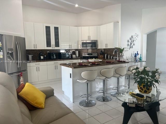 9435 Southwest 156th Place, Unit 9435 Miami, FL 33196 - Photo 16 of 28 a kitchen with stainless steel appliances kitchen island granite countertop a sink and cabinets
