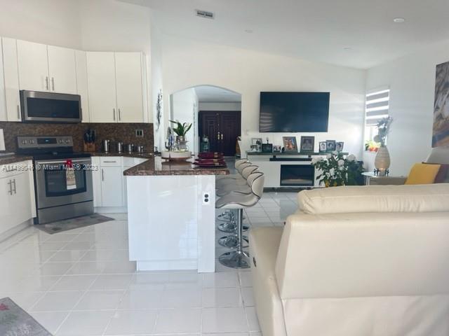 9435 Southwest 156th Place, Unit 9435 Miami, FL 33196 - Photo 19 of 28 a kitchen with a stove top oven and cabinets