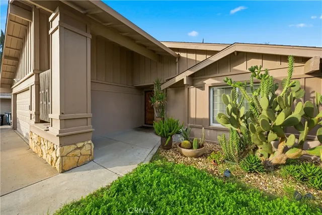 a view of a house with a small yard and floor to ceiling window and potted plants