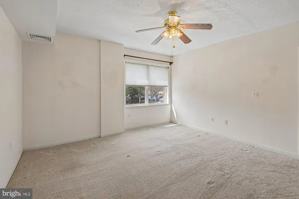 an empty room with a window and a ceiling fan