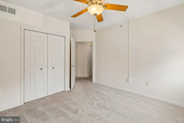 an empty room with a ceiling fan and closet