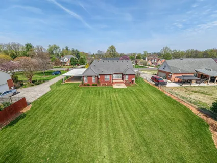 a view of a house with a big yard and large trees