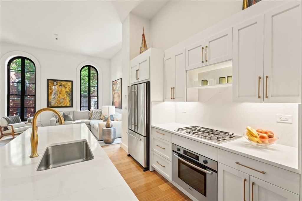 21 Father Francis Gilday Street, Unit 114 Boston, MA 02118 - Photo 3 of 28 a kitchen with stainless steel appliances granite countertop a white stove top oven a sink a refrigerator and white cabinets with wooden floor