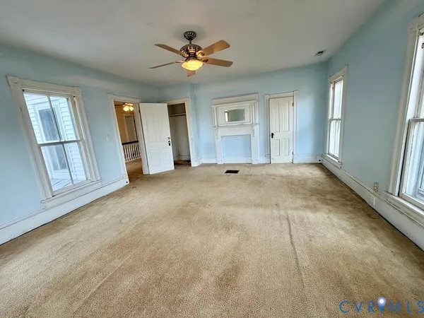 an empty room with windows and ceiling fan
