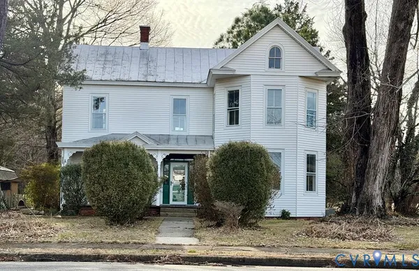 a view of a white house with a small yard and large tree