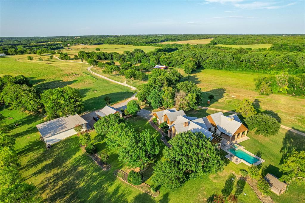 1922 A Bethel-Cannon Road Whitewright, TX 75491 - Photo 39 of 40 Expansive property featuring a main residence with a metal roof, a rectangular swimming pool, and multiple outbuildings