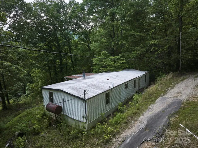 a wooden house with a yard and large trees