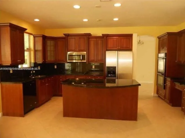 a large kitchen with stainless steel appliances granite countertop a stove a refrigerator a sink and a microwave