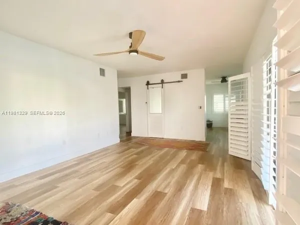 a view of empty room with wooden floor and fan