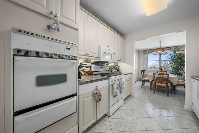 a kitchen with granite countertop white cabinets and white appliances