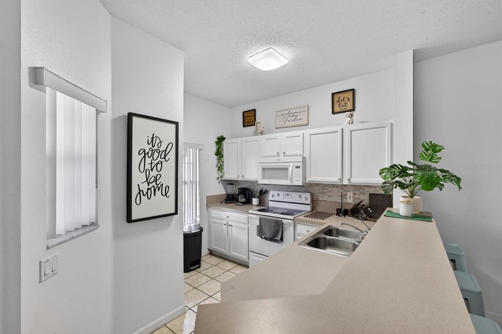 1066 Park Ridge Circle Kissimmee, FL 34746 - Photo 48 of 49 a kitchen with stainless steel appliances a white refrigerator a stove top oven a potted plant and a window