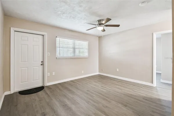 an empty room with wooden floor fan and windows