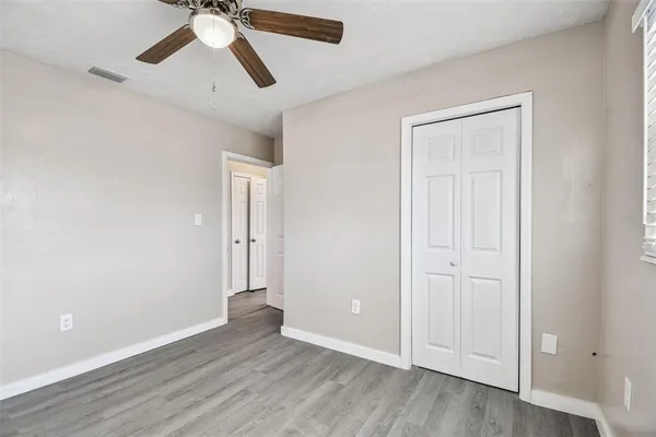an empty room with wooden floor ceiling fan and windows