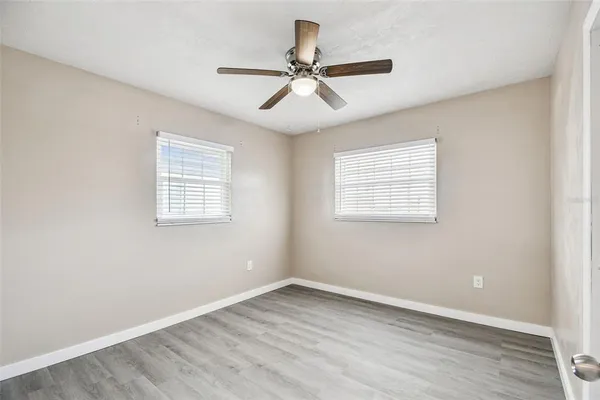 an empty room with wooden floor window and ceiling fan