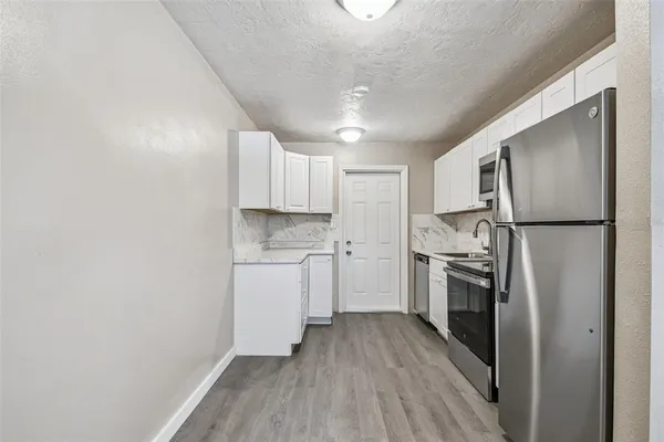 a kitchen with a refrigerator a sink and dishwasher a stove top oven with wooden floor