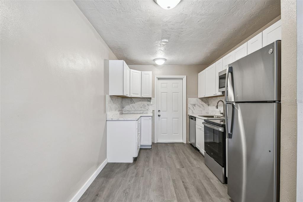 337 4th Street West, Unit A Palmetto, FL 34221 - Photo 20 of 25 a kitchen with a refrigerator a sink and dishwasher a stove top oven with wooden floor