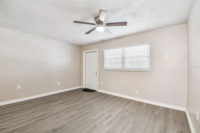 an empty room with wooden floor ceiling fan and windows