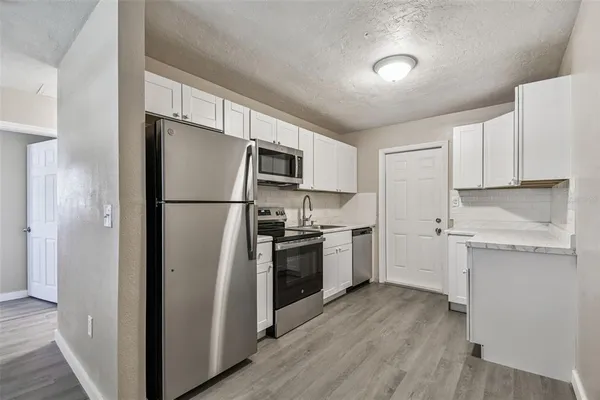 a kitchen with a refrigerator stainless steel appliances wooden floor and cabinets