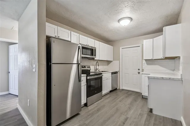 a kitchen with a refrigerator stainless steel appliances wooden floor and cabinets