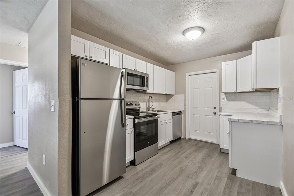 337 4th Street West, Unit A Palmetto, FL 34221 - Photo 9 of 25 a kitchen with a refrigerator stainless steel appliances wooden floor and cabinets