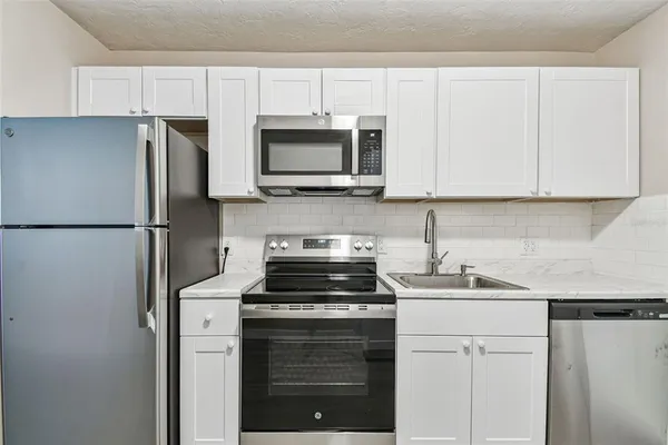 a kitchen with a refrigerator stove and white cabinets