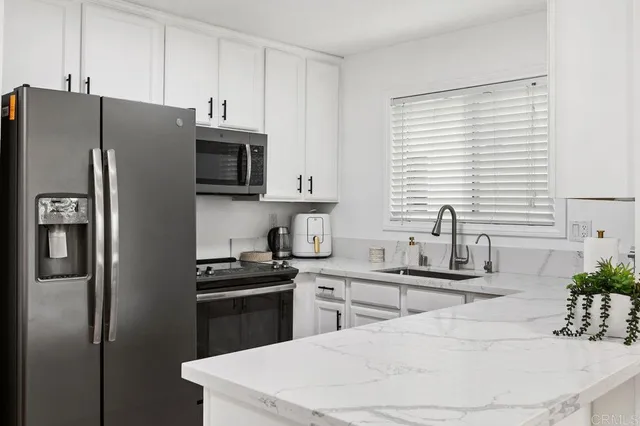 a kitchen with stainless steel appliances a table chairs and a refrigerator