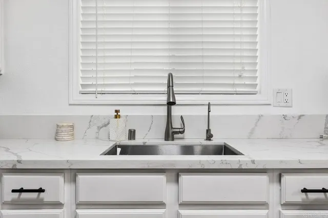 a kitchen with stainless steel appliances kitchen island granite countertop a sink a stove a dining table and chairs with wooden floor