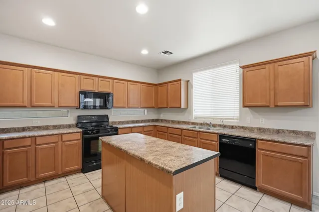 a view of a kitchen with kitchen island granite countertop a sink cabinets and window