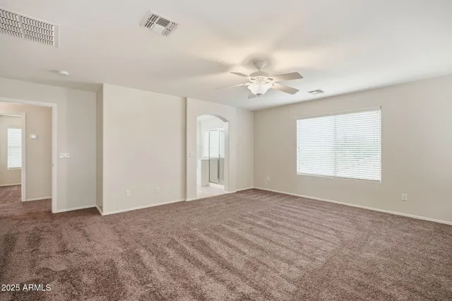 an empty room with windows and chandelier fan